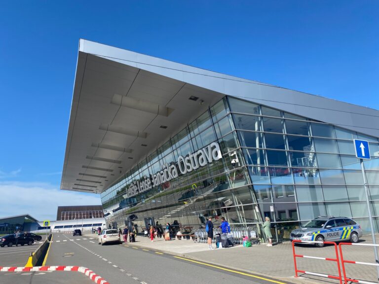 Exteriér terminálu Letiště Leoše Janáčka Ostrava s nápisem na fasádě a přistavenými auty před vchodem.