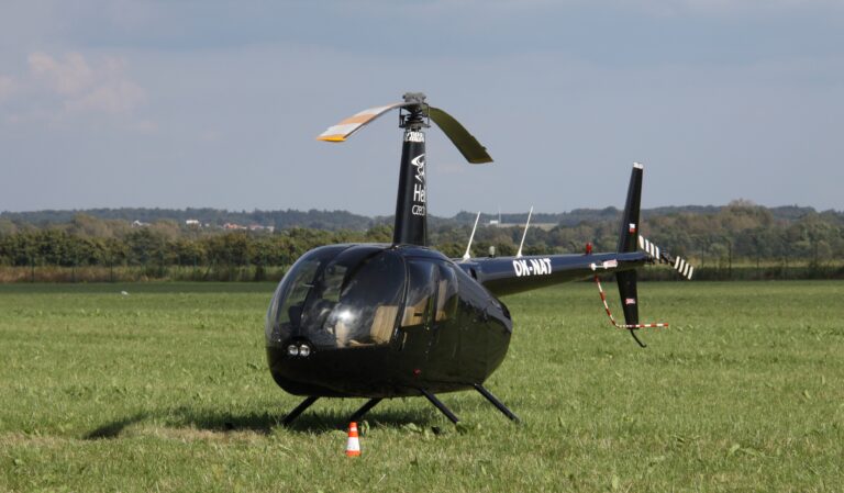 Černý vrtulník Robinson R44 na travnaté ploše Letiště Leoše Janáčka Ostrava.