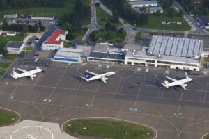 Letecký pohled na odbavovací plochu Letiště Leoše Janáčka Ostrava se třemi stojícími letadly před budovou terminálu
